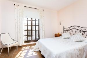 una camera da letto con un letto, una sedia e una finestra di Home2Book El Médano Cozy Beach & Wifi a El Médano
