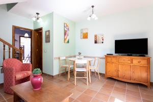 sala de estar con TV y mesa con sillas en Home2Book El Médano Cozy Beach & Wifi, en El Médano