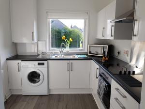 a white kitchen with a sink and a washing machine at Flemming Place in East Kilbride