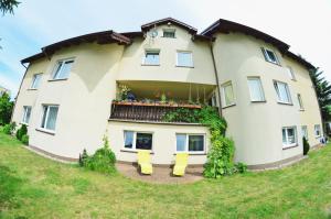 a large white house with yellow chairs in front of it at IWONA Pokoje Apartamenty in Karwia