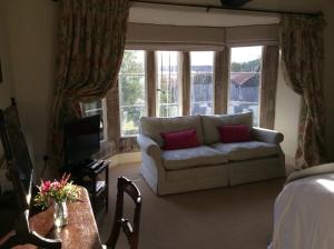 a living room with a couch and some windows at Castle Farm House B&B in Corby
