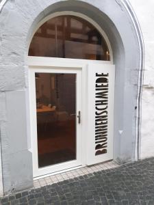białe drzwi z znakiem na boku budynku w obiekcie Brunnenschmiede w Konstancji
