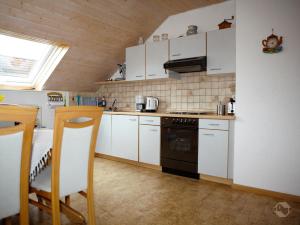een keuken met witte kasten en een fornuis met oven bij Ferienwohnung Schillinger in Sasbach am Kaiserstuhl