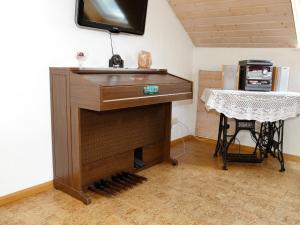 a wooden piano in a room with a table and a television at Ferienwohnung Schillinger in Sasbach am Kaiserstuhl