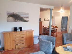 a living room with chairs and a wooden dresser at Ferienwohnung 4 im Haus am See mit Wintergarten und Terrasse in Seedorf