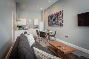 Gordon Moon Suites Bolton Centre Apartments في بولتون: غرفة معيشة مع أريكة وطاولة