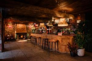 a bar with stools in a room with a fireplace at The Joiners Arms in Chathill