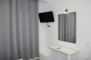 uma casa de banho com uma televisão e uma cortina de chuveiro em Zeus Hotel em Iraion