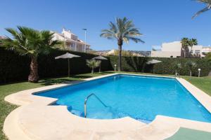 einen Pool in einem Garten mit Palmen in der Unterkunft Ático dúplex cerca del Arenal (Jávea) in Aduanas