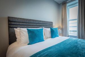 a bedroom with a large bed with blue pillows at Gordon Moon Suites Bolton Centre Apartments in Bolton