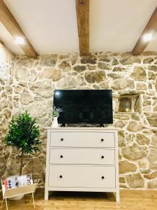 a tv on a dresser in a room with a stone wall at APARTMAN Captain Bervida Murter in Murter