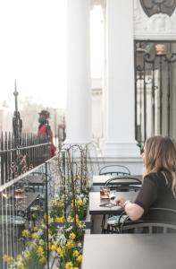 a woman sitting at a table looking at her cell phone at The Cadogan, A Belmond Hotel, London in London
