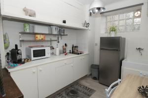 kuchnia z białymi szafkami i lodówką ze stali nierdzewnej w obiekcie Studio avec vue sur les arénes w mieście Arles