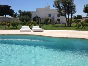 uma piscina com duas espreguiçadeiras em frente a uma casa em Masseria Ancella em Montalbano