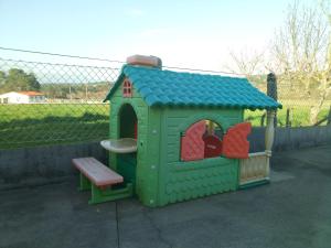 une petite maison de jeu verte avec un banc et une clôture dans l'établissement Casa Socorro, à A Estrada