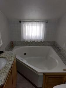 a white bath tub in a bathroom with a window at Pousada Agradável Pomerode in Pomerode
