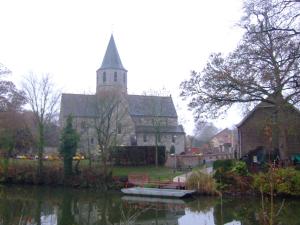 uma igreja com um campanário e um barco na água em GUESTROOMS BIJ HET STATION VAN DRONGEN em Gante