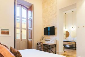 a living room with a desk and a television in a room at VEINTIUNO Emblematic Hotels - Adults Only in Las Palmas de Gran Canaria