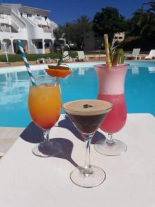 three cocktails sitting on a table next to a pool at Vilamar in Luz