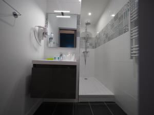 y baño blanco con lavabo y ducha. en Hôtel Le Biarritz - Vichy en Vichy