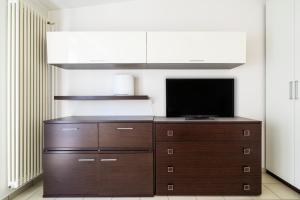 Zimmer mit einem TV auf einer Holzkommode in der Unterkunft PrimoPiano - Garofalo A in Mailand