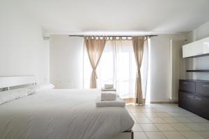 ein weißes Schlafzimmer mit einem großen Bett und einem Fenster in der Unterkunft PrimoPiano - Garofalo A in Mailand