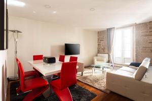 ein Wohnzimmer mit einem weißen Tisch und roten Stühlen in der Unterkunft Luxury apartment-free parking in Santiago de Compostela