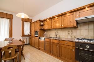 a large kitchen with wooden cabinets and a table at Villa Marmarole a Calalzo in Calalzo