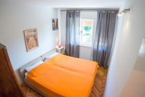 ein orangefarbenes Bett in einem kleinen Zimmer mit Fenster in der Unterkunft Studio Apartman Filipa in Jadranovo