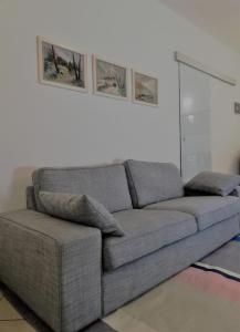 un sofá gris en una sala de estar con dos cuadros en la pared en Il Melograno, en Rímini