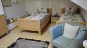 1 dormitorio con 2 camas y silla azul en Zimmer Schmitz, en Anschau