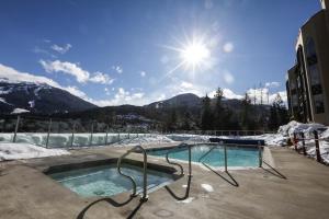 una piscina con montañas cubiertas de nieve en el fondo en The Ironwood on Blueberry Hill, en Whistler