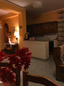 a living room with a kitchen and a table with red flowers at B&B da nonna Vincenza in Vinchiaturo