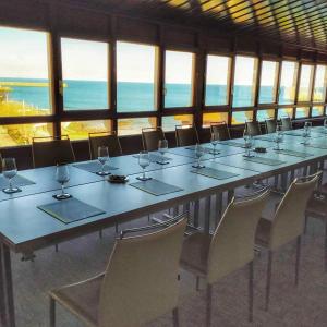 a large long table with chairs and wine glasses at Las Rocas Playa Hotel in Castro-Urdiales