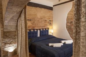 um quarto com uma cama azul e uma parede de tijolos em Camere La Basilica em Assis