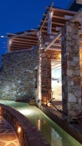 a stone house with a pool of water at night at Vrahos Boutique Hotel in Karavostasi