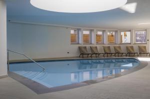 ein Pool in einem Gebäude mit Stühlen drumherum in der Unterkunft Hotel Alaska in Campitello di Fassa