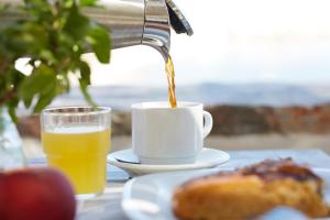 a cup of coffee and a plate of orange juice at Vrahos Boutique Hotel in Karavostasi