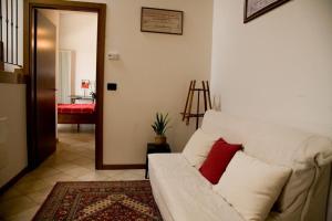 ein Wohnzimmer mit einem weißen Sofa und einem roten Kissen in der Unterkunft B&B Corte Alfier in Mortegliano