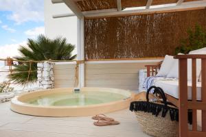 a jacuzzi tub on a patio with a bed at Vrahos Boutique Hotel in Karavostasi +37 photos