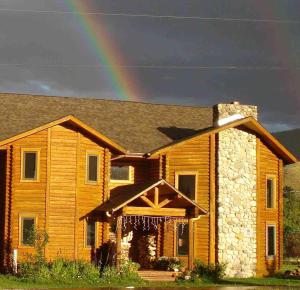 a rainbow over a wooden house with at Inn on the Beartooth B&B in Red Lodge