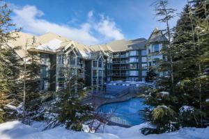 a resort in the snow with a swimming pool and trees at The Woodrun Lodge by Whiski Jack in Whistler