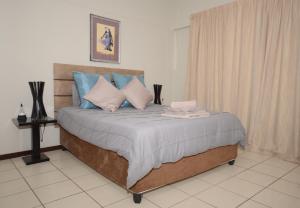 a bedroom with a bed with blue and white pillows at Libem Lodge 2 in Edenvale