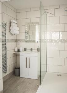 een witte badkamer met een wastafel en een douche bij The Darling Suites in Filey