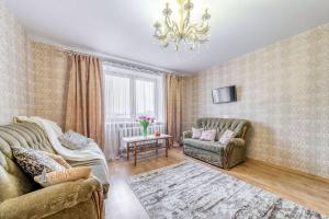 Helen Apartments Galleria Minsk في مينسك: غرفة معيشة بها كنبتين وثريا