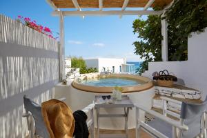 a hot tub on a patio with a table and chairs at Vrahos Boutique Hotel in Karavostasi
