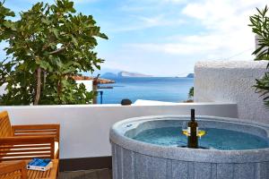 a hot tub with a bottle of wine in it on a patio at Vrahos Boutique Hotel in Karavostasi
