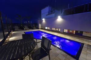 a swimming pool at night with a table and chairs at Via Garden Varginha Hotel in Varginha
