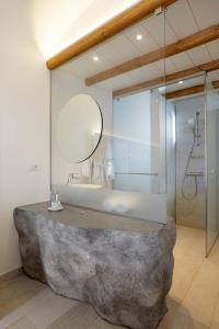 a bathroom with a large stone tub and a mirror at Vrahos Boutique Hotel in Karavostasi