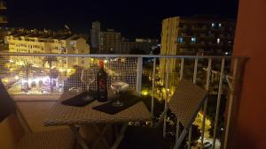 ベナルマデナにあるApartamentos Minerva- Jupiterの夜のバルコニーにテーブルとワイングラス